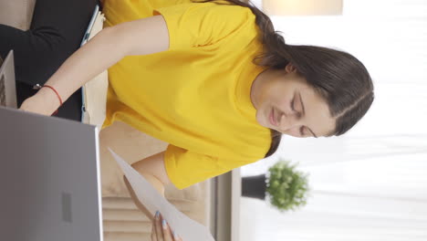 Vertical-video-of-Female-student-working-between-paper-and-laptop.